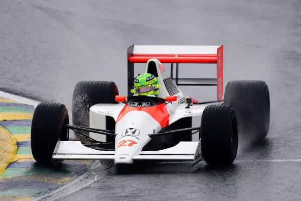 Foto colorida de Lewis Hamilton conduzido o carro McLaren MP4/5B, em que Ayrton Senna venceu o campeonato da Fórmula 1 de 1990 - Metrópoles