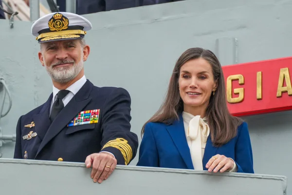 Foto colorida de homem com traje da Marinha ao lado de mulher com blazer azul e blusa branca. Eles estão em um navio - Metrópoles