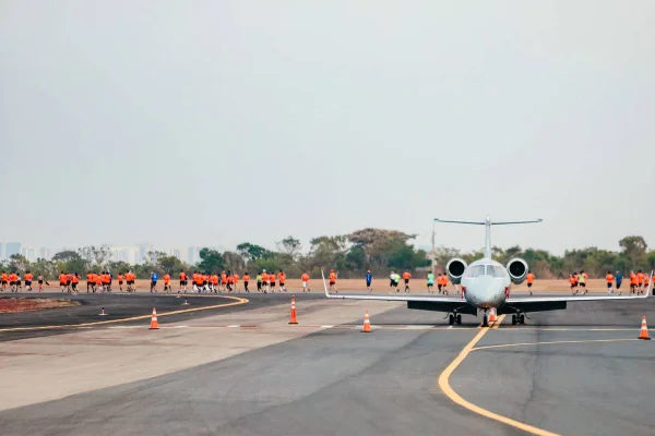 Fotografia colorida mostrando pessoas correndo atrás de avião-Metrópoles