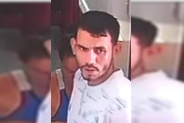 Imagem de um homem branco, com cabelos curtos e barba curta, camiseta branca com detalhes pretos