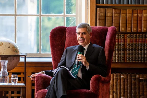 Imagem de Mohamed El-Erian, presidente do Queen’s College em Cambridge e conselheiro econômico-chefe da Allianz, sentado em uma poltrona vermelha, falando ao microfone. Ele veste um terno escuro, camisa branca e gravata verde, e tem cabelos grisalhos - Metrópoles