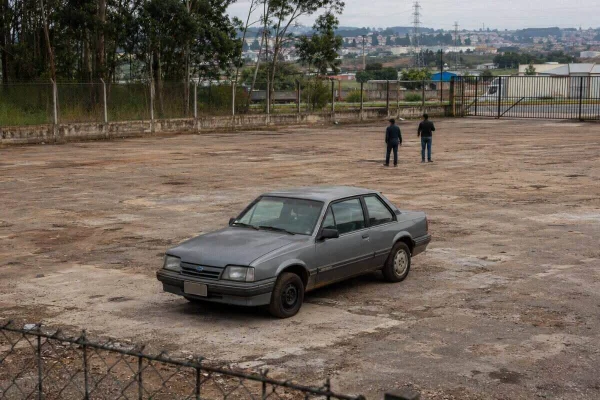 Arte gráfica de carro solitário em meio a um pátio de veículos - Metrópoles