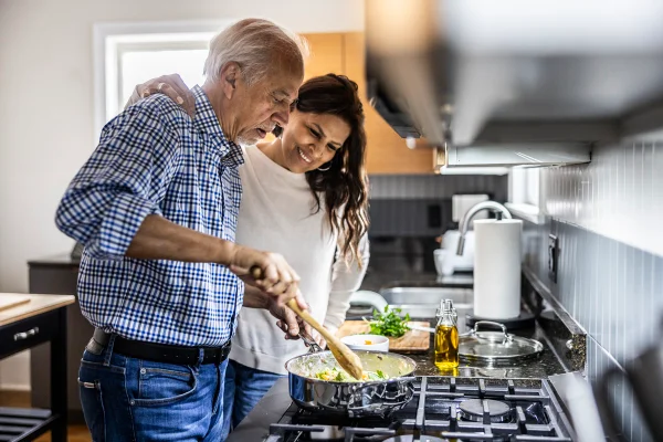 Foto colorida de homem cozinhando em um fogão e há uma mulher ao lado - Metrópoles