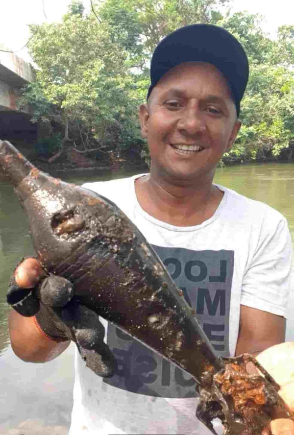 Na imagem, o pescador Izaak Soares segura a bomba de guerra que encontrou no rio Guaporé