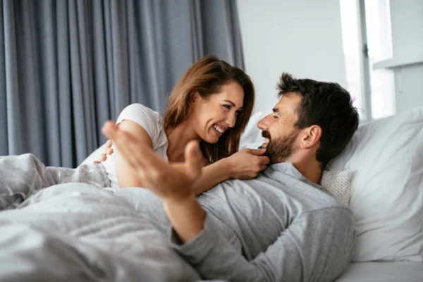 Imagem colorida de pessoas deitadas na cama, flertando