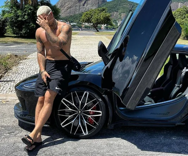 Imagem colorida do rapper Filipe Ret sentado no capô de um McLaren GT - Metrópoles