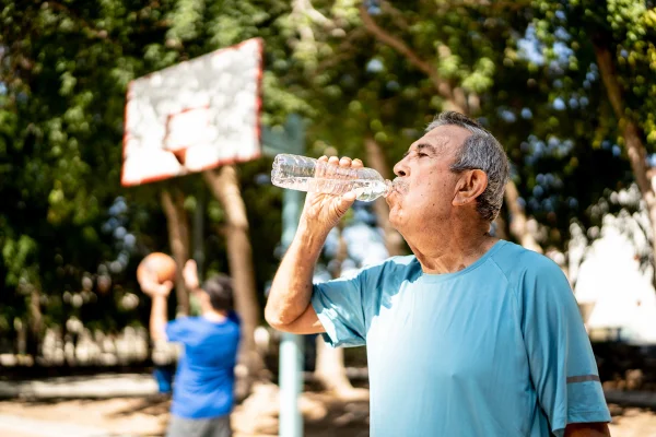 Senhor idoso bebendo água na quadra de basquete. Metrópoles