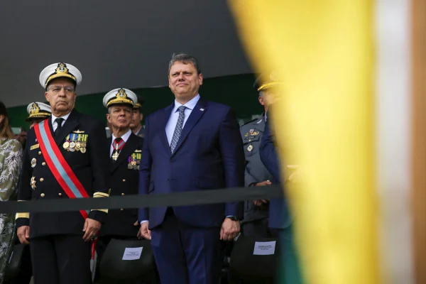 Imagem colorida mostra o governador Tarcísio de Freitas, homem branco, grisalho, de terno azul, cercado de militares de uniforme de gala, no palco do desflie de 7 de setembro - Metrópoles