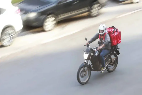 Foto colorida de motoboy na rua