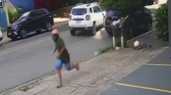 Homem de capacete corre pela calçada ao ser perseguido por PM; outro homem, também de capacete, caído - Metrópoles