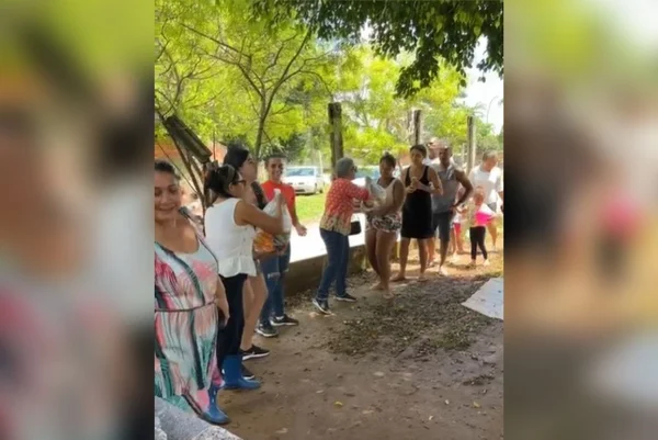 Imagem colorida de pessoas passando cesta básica de mão em mão - Metrópoles