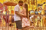 Paulinha Leite e o marido, Dakota Ballard, dão beijão em frente a um carrossel 