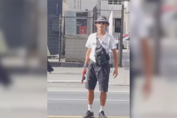 Imagem colorida de um homem branco vestido com uma camiseta do Brasil e portando uma arma de brinquedo. Ele é acusado de homofobia - Metrópoles