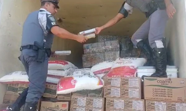 Imagem colorida mostra dois policiais dentro de caçamba de caminhão recolhendo pacotes de cocaína durante apreensão na rodovia Raposo Tavares, em São Paulo - Metrópoles