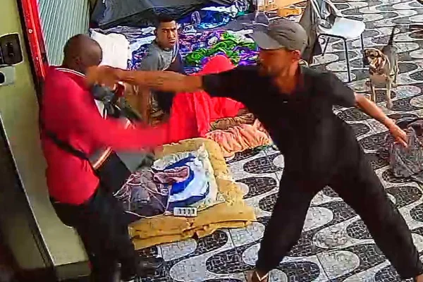 homem de camiseta preta acerta golpe em rosto de homem de casaco vermelho