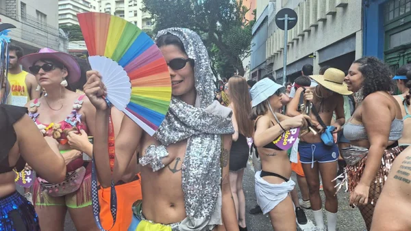 Foto colorida de mulher fantasiada segurando leque durante desfile de bloco de rua no Carnaval de São Paulo - Metrópoles