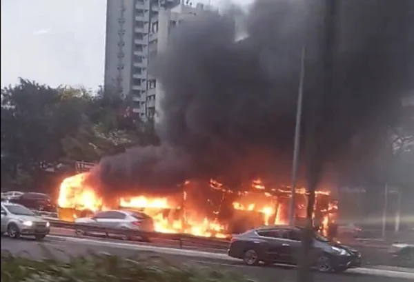 Imagem colorida de ônibus coberto pelo fogo e com fumaça preta acima em via movimenta de São Paulo - Metrópoles
