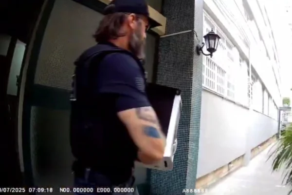 Imagem colorida de policial do Deic conduzindo uma CPU apreendida. Metrópoles