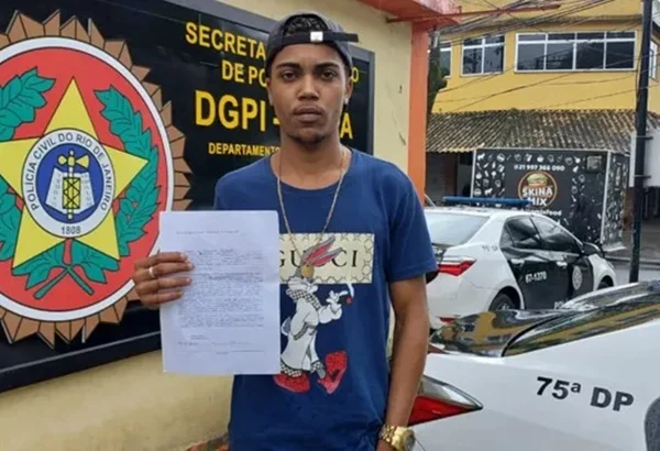 Imagem mostra homem negro segurando boletim de ocorrência em frente a uma delegacia, por ter sido vítima de fake news| Metrópoles