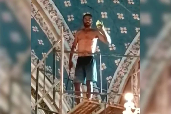 Imagem colorida mostra homem sem camisa em cima de andaime dentro de igreja; ele acabou baleado e morreu - Metrópoles