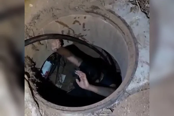 Imagem colorida de um homem dentro de um bueiro - Metrópoles