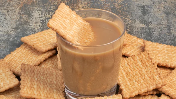 Biscoitos caseiros espalhados ao lado de corpo de leite com café