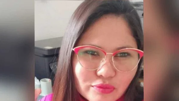 selfie de uma mulher. ela olha batom rosa e óculos de grau e tem o cabelo preto e liso