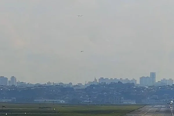 Imagem colorida mostra avião e helicóptero próximos em manobra perto do aeroporto de Guarulhos. O avião precisou arremeter - Metrópoles