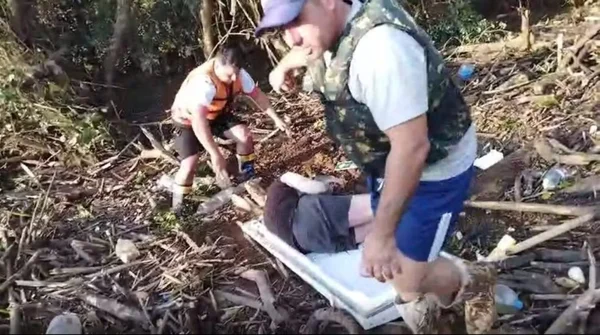 Foto colorida retirada de vídeo que mostra João Emiliano Salamoni sendo resgatado mãe e filho - Metrópoles