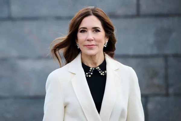 Princesa Mary, uma mulher branca, dinamarquesa, de cabelos castanhos escuros. Ela está usando um sobretudo branco e uma roupa preta por baixo - Metrópoles