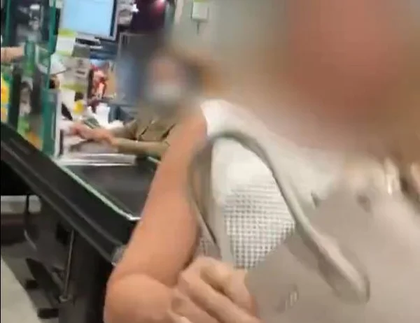 Mulher com bolsa ao lado de caixa de supermercado