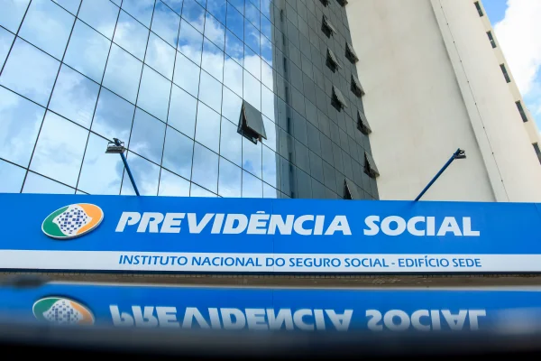 Fachada da Previdência Social e acesso digital aos serviços do INSS pelo aplicativo Meu INSS - Mertrópoles