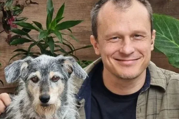 Foto colorida de um homem ao lado de um cachorro - Metrópoles