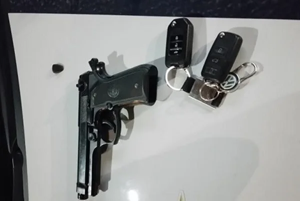 Arma e chaves de carro em capô