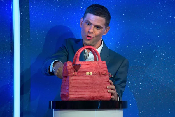 na foto vemos um homem cortando uma bolsa feita de bolo