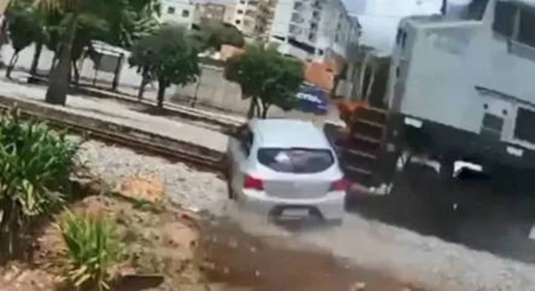 print de um vídeo que mostra em trem atingindo um carro prateado em uma ferrovia