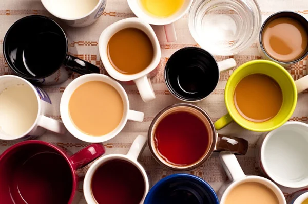 Várias xícaras de café com cores diferentes sendo fotografadas de cima cafeína