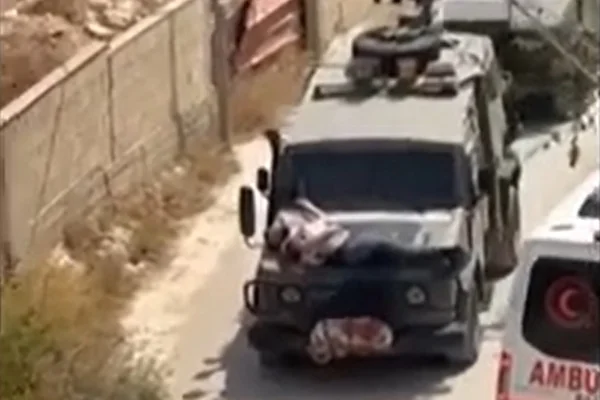 Foto colorida de corpo amarrado em carro do exército israelense - Metrópoles