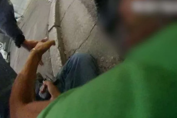 Imagem colorida de homem no chão com arma na mão. Metrópoles