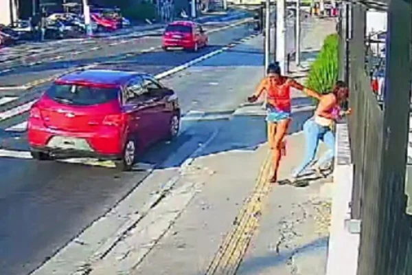 Imagem colorida de duas mulheres trans correndo em calçada - Metrópoles