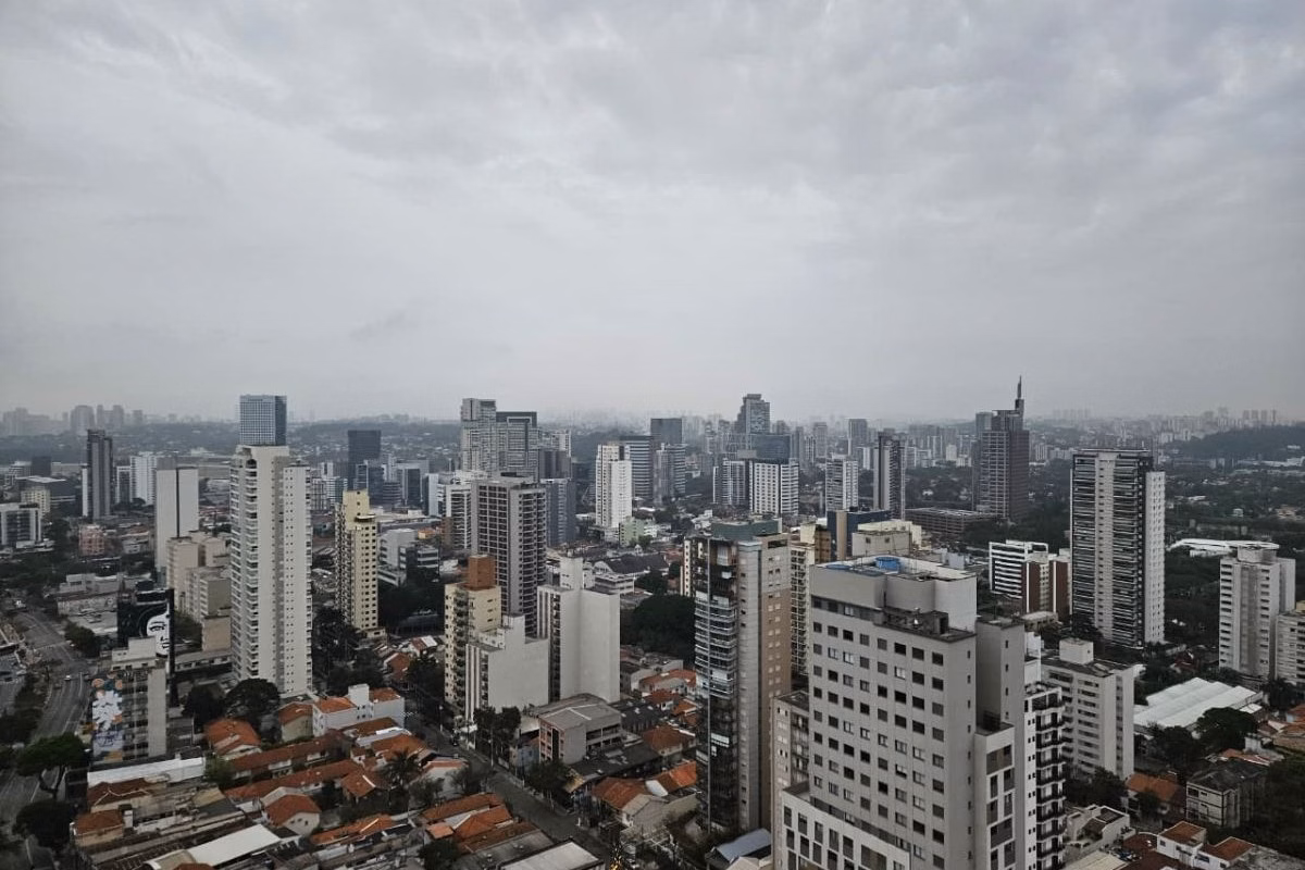Céu com nuvens cinzas sobre cidade de São Paulo; diversos prédios cobertos por leve neblina - Metrópoles