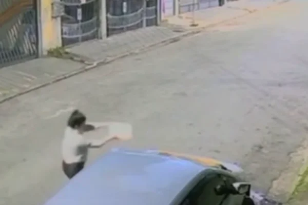 Imagem colorida de mulher jogando gasolina no carro do namorado depois de descobrir traição. Metrópoles