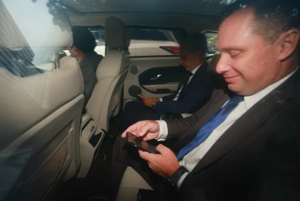 Imagem colorida de Mauro Cid sorrindo, dentro de carro e olhando para o celular - Metrópoles
