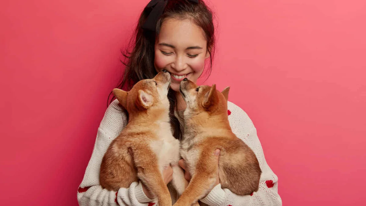 menina segurando ccachorros no colo e sorrindo pra eles - Metrópoles