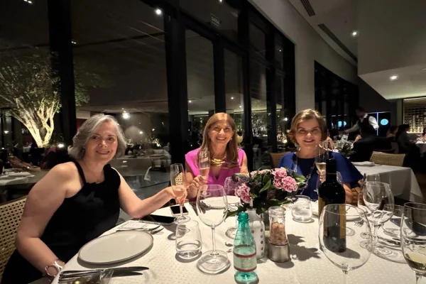 Foto colorida trio de amigas sentadas a mesa