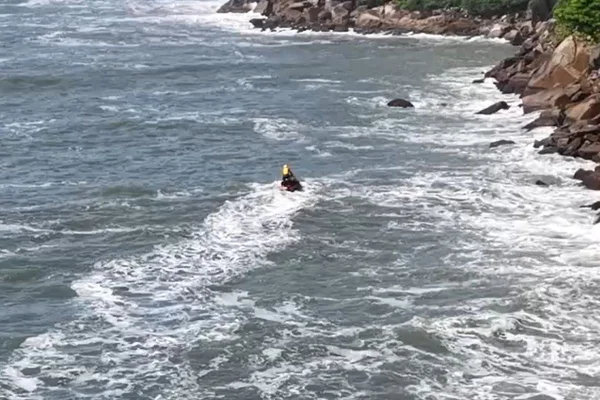 Imagem colorida mostra busca de bombeiros por turista desaparecida no Guarujá. Metrópoles