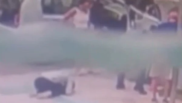 Imagem colorida mostra uma mulher ajoelhada no chão; ela é mãe de um bebê engasgado que está sendo salvo por um PM - Metrópoles