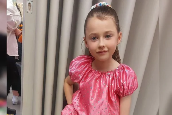 Foto mostra menina na primeira infância vestida de rosa contra um fundo neutro - Metrópoles