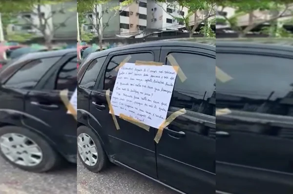 foto de uma cartolina pregada na lateral de um carro preto com fita adesiva