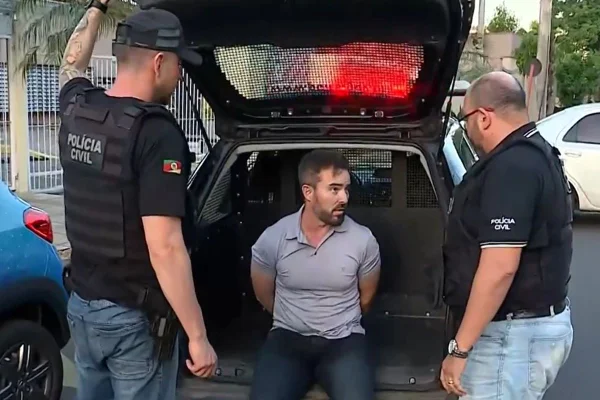 Imagem colorida de homem detido na parte traseira de viatura - Metrópoles